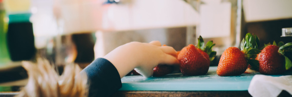 A kid grabbing food in the kitchen