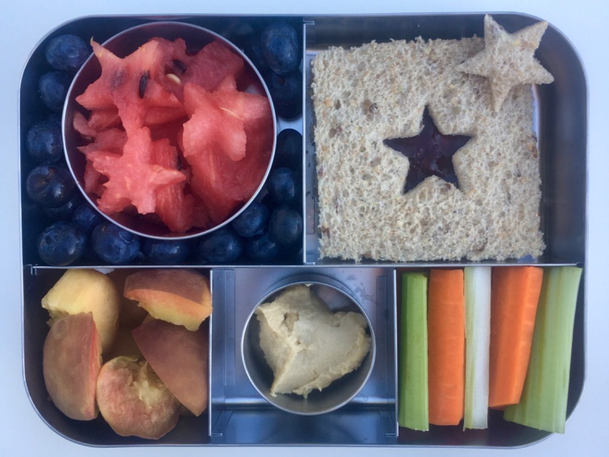 4th of July vibes with this creative kid's bento lunchbox containing a sandwich, fruits, veggies, and hummus
