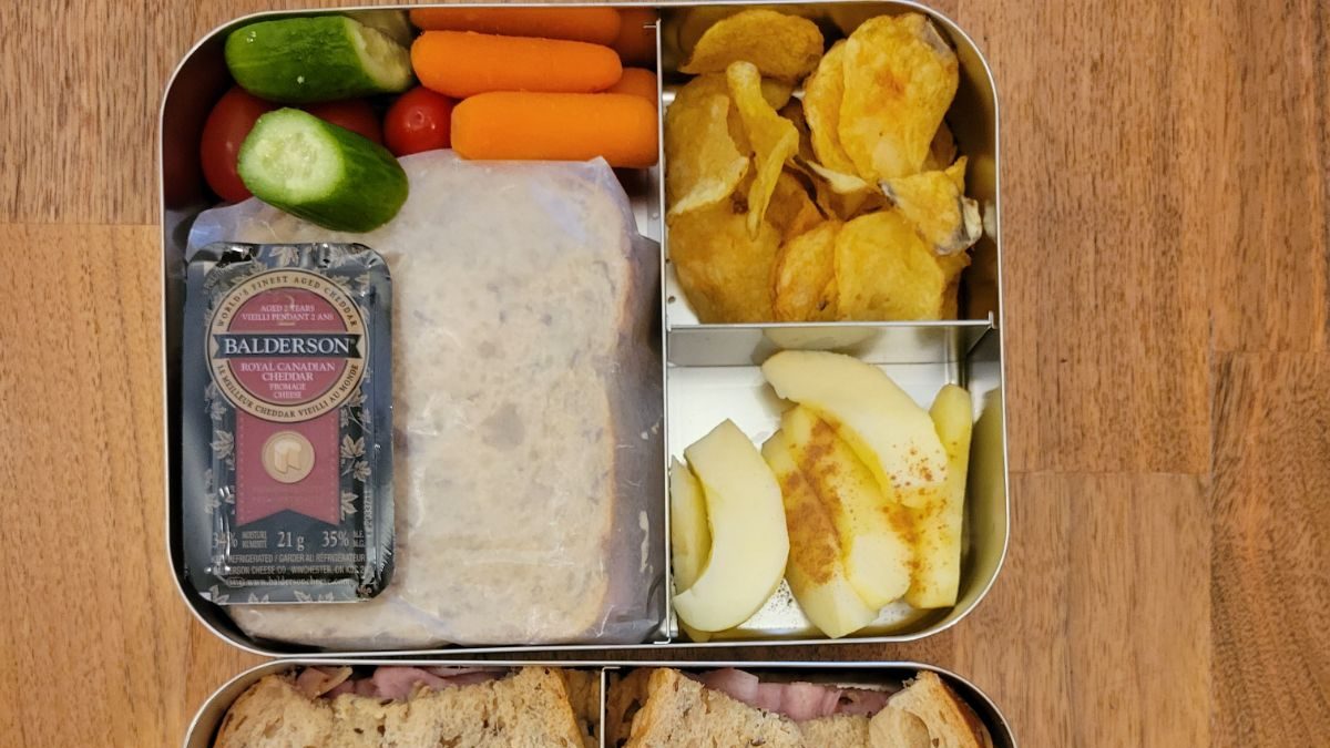 apple slices and baby carrots among other kid-friendly foods in a Lunchbot stainless steel bento lunchbox