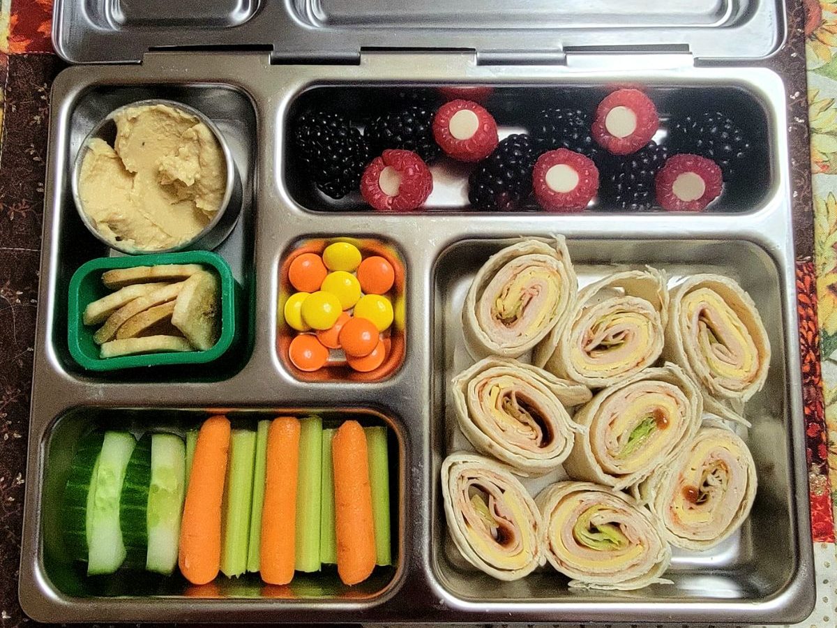 Banana chips and celery sticks, with tortilla rolls in a Planetbox bento lunchbox for a kid's lunch at school