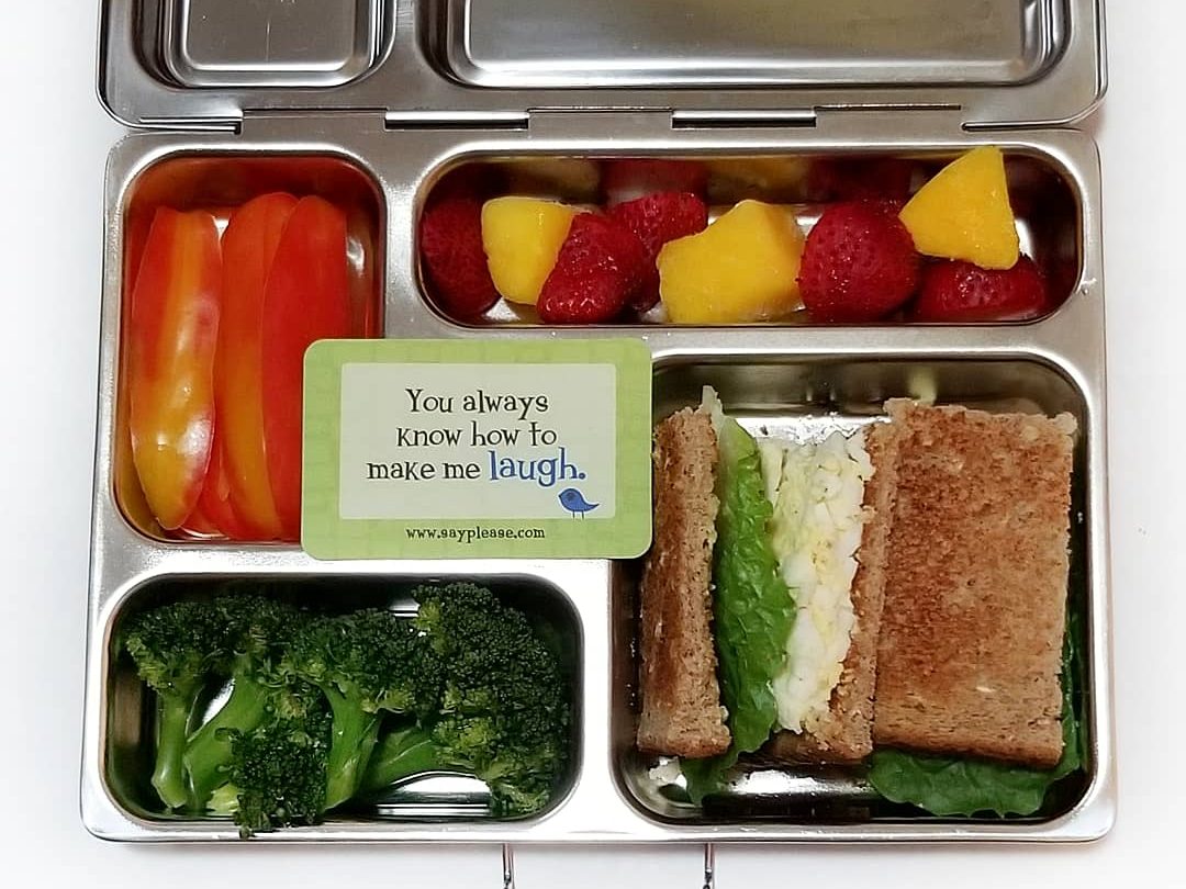 mango and bell pepper in a kid's lunchbox with cheese spinach sandwich and broccoli