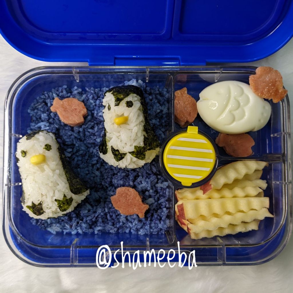 Two penguin rice balls in a blue Yumbox lunchbox