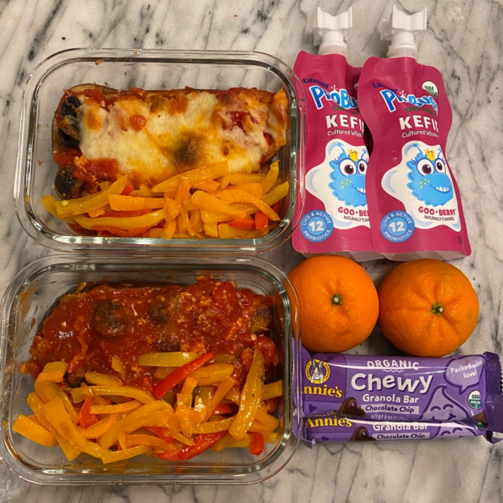 Mandarin oranges next to a delicious baked eggplant lunchbox, symbolizing prosperity and good fortune.