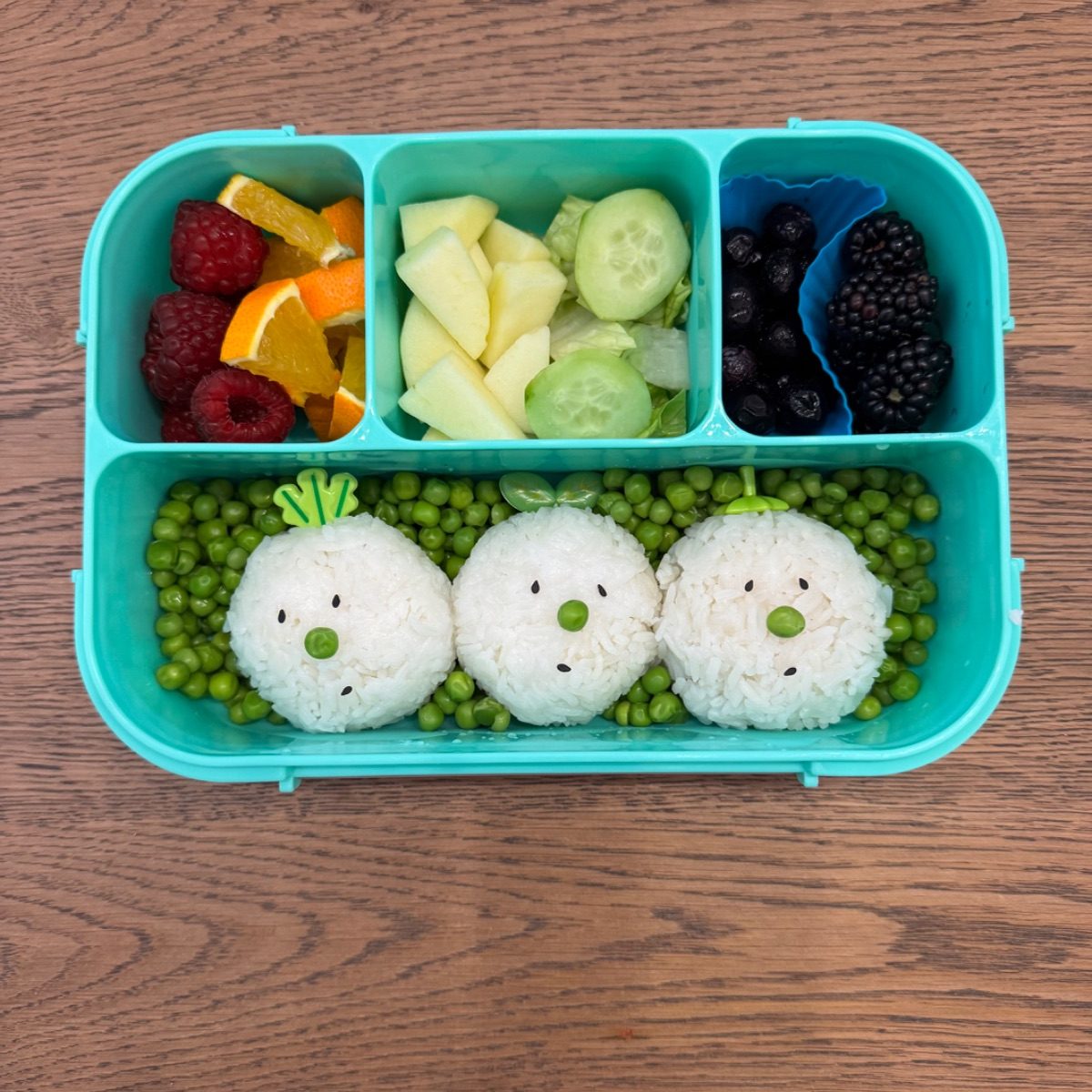 Cute rice balls on a bed of green peas for a kid's lunchbox