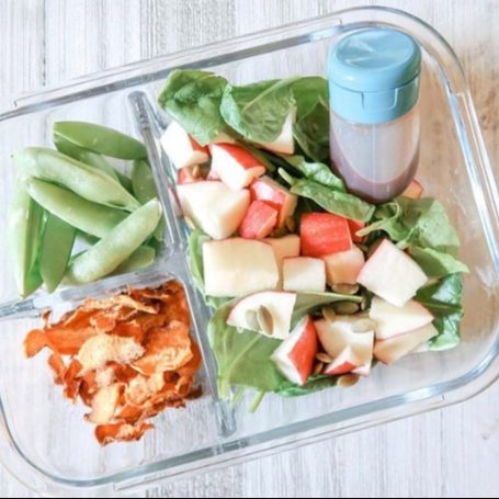 Spinach and apple salad in a glass lunchbox