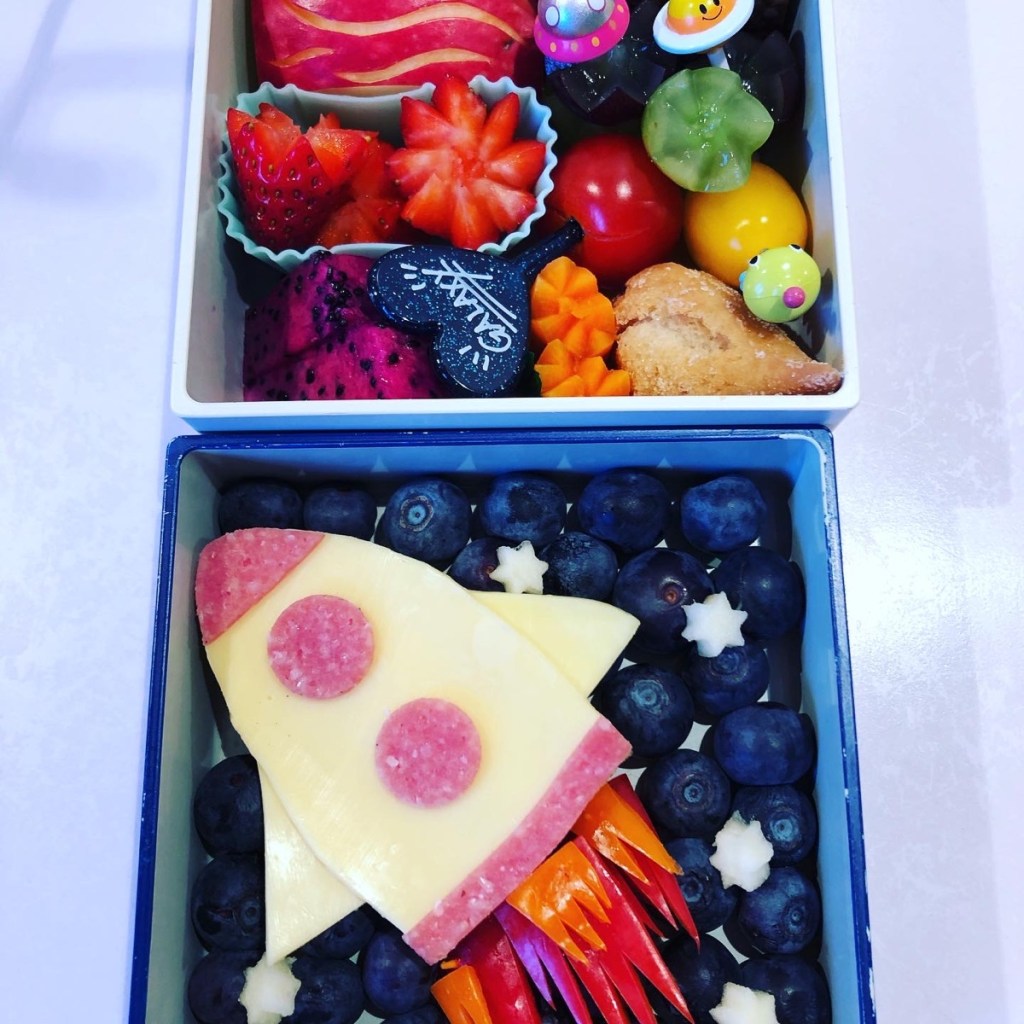 Cheese and salami rocketship on a bed of blueberries for a fun space-themed lunch at school.