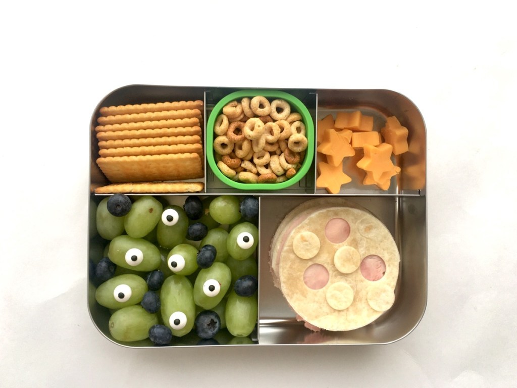 Out of this world lunch for a kid with moon tortilla bite, cheddar stars, and aliens fruits.