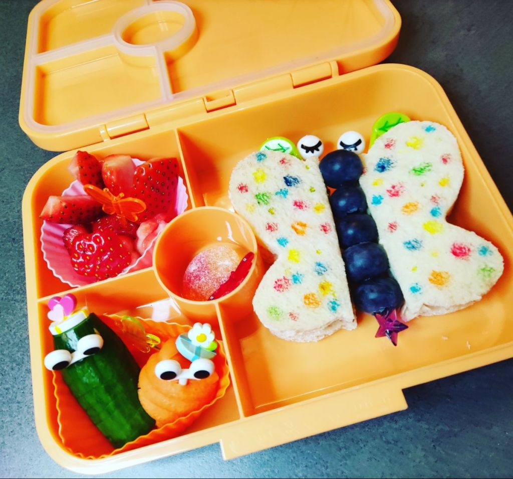 Bento lunchbox with butterfly sandwich, fruit skewers for the body, and fun fruit and veggie snacks.