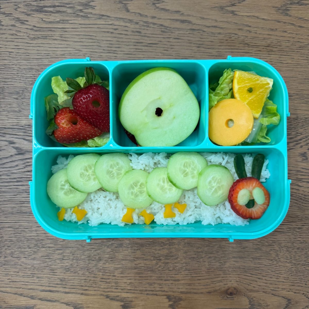 The very hungry caterpillar made of cucumber and watermelon in a kid's bento lunchbox