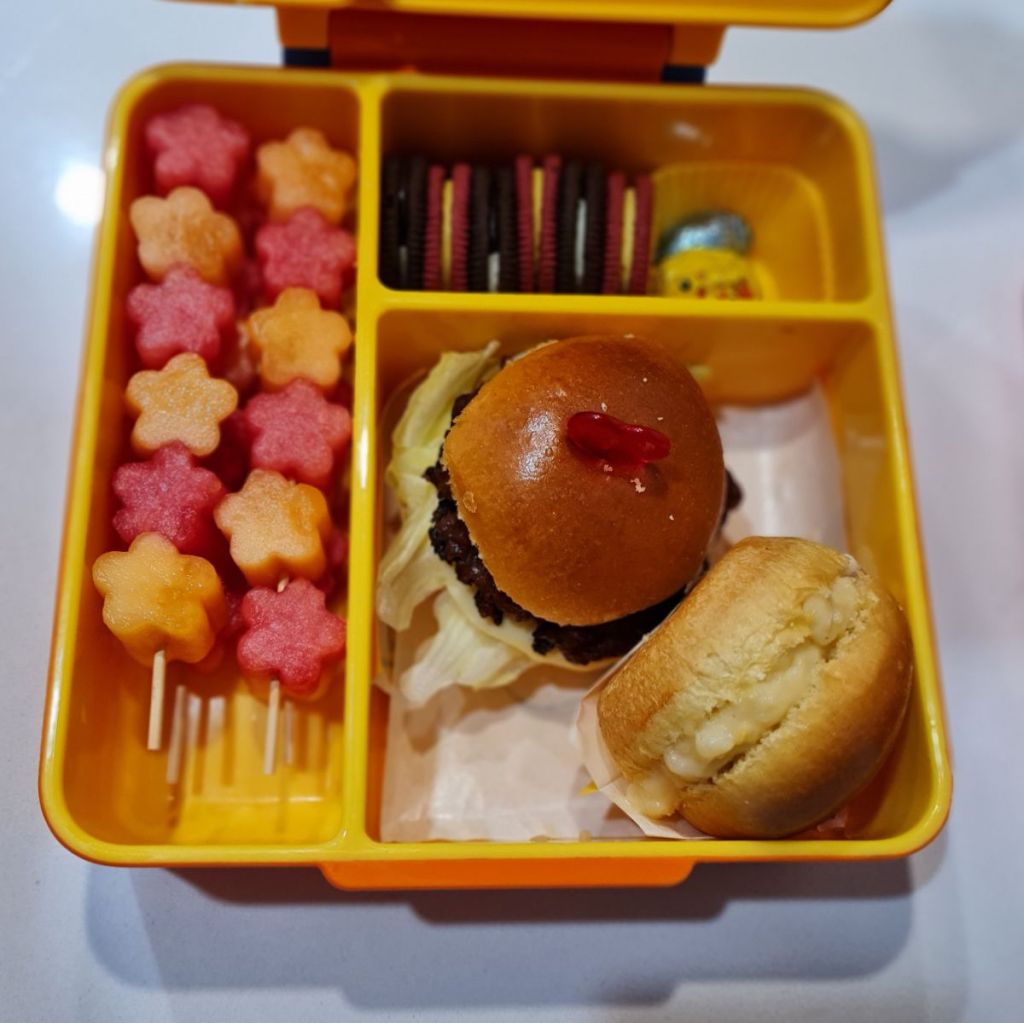 Excursion lunchbox for a kid with mini burgers and fresh fruits skewers.